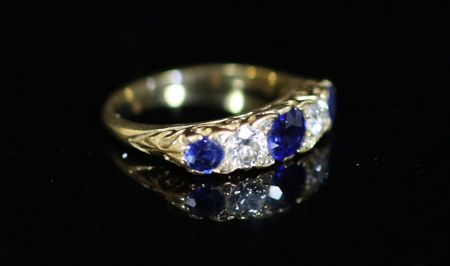 An early 20th century three stone sapphire and two stone diamond set half hoop ring